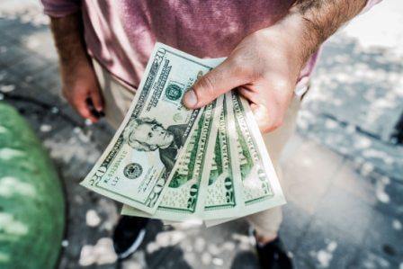 Man holding 4 20-dollar bank notes