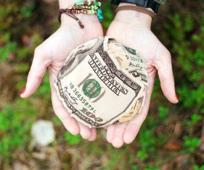 2 hands with 100 dollar bank notes