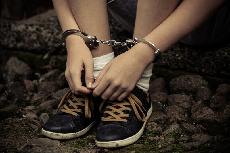 Young boy in handcuffs, only hands and foots on photo