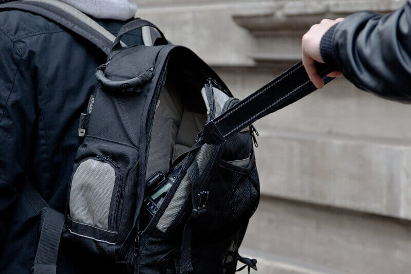 Thieve's hand steeling camera fom someone's backpack